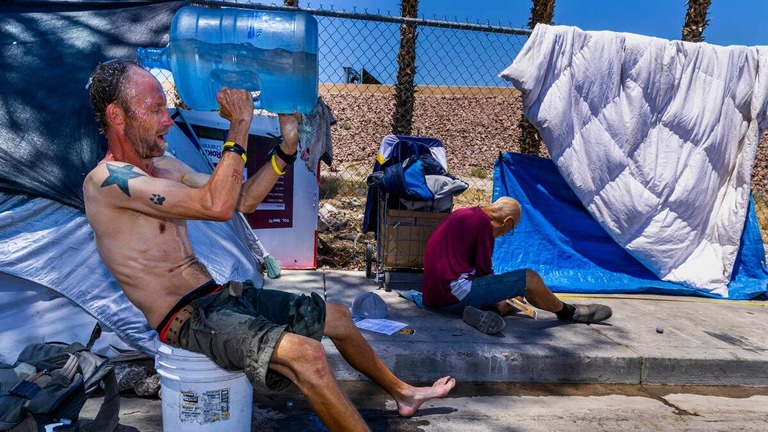 米ネバダ州ラスベガスで頭から水をかぶり暑さをしのぐ男性/L.E. Baskow/Las Vegas Review-Journal/Tribune News Service/Getty Images