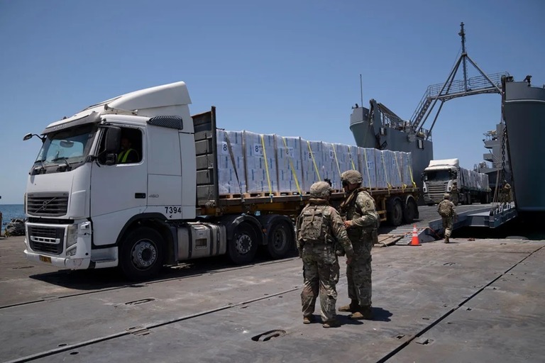 米国が建設した浮桟橋に到着したトラック＝２５日/Leo Correa/AP